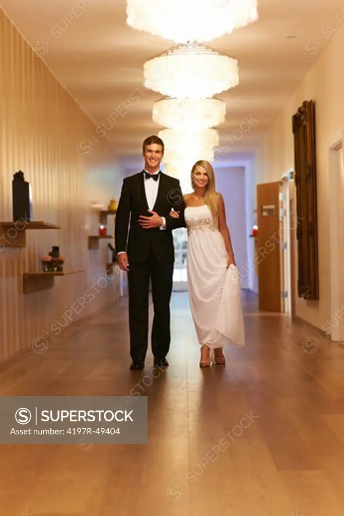 Portrait of a gorgeous couple walking down a chandelier corridor on their way to a banquet