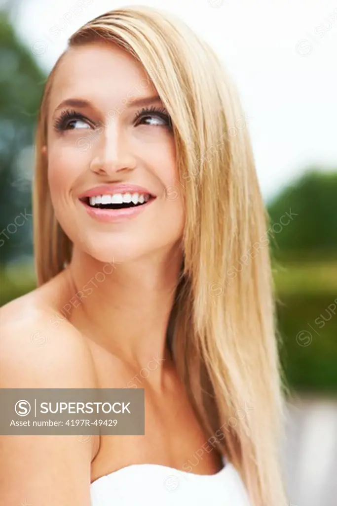 Closeup of a stunning young woman with a dazzling, white smile looking away