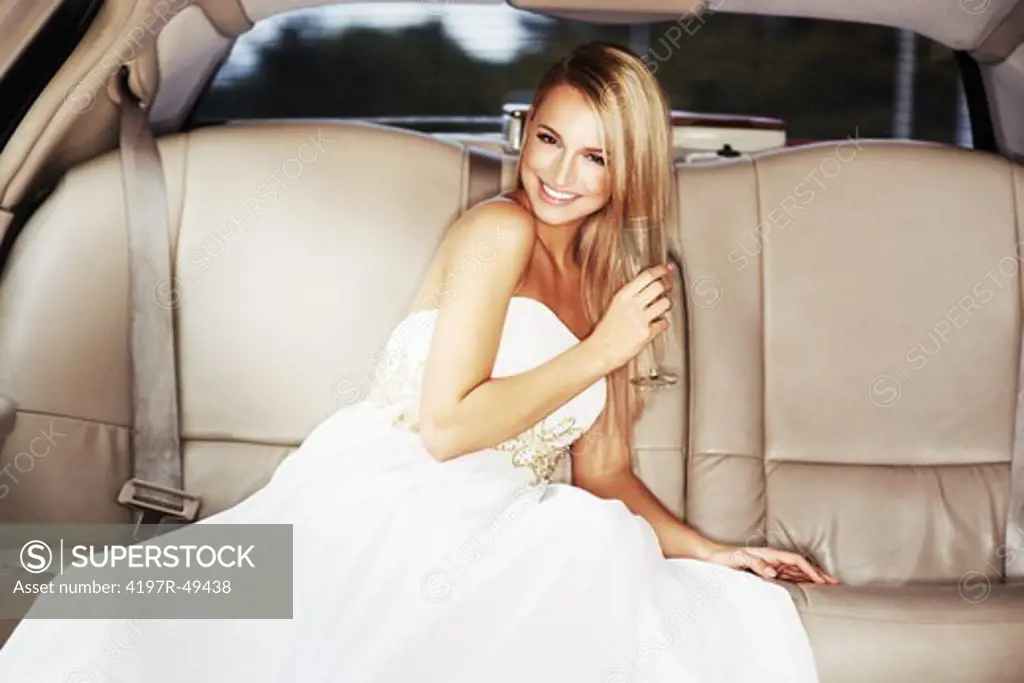 A gorgeous young woman enjoying a glass of champagne while sitting in the luxury of a limousine