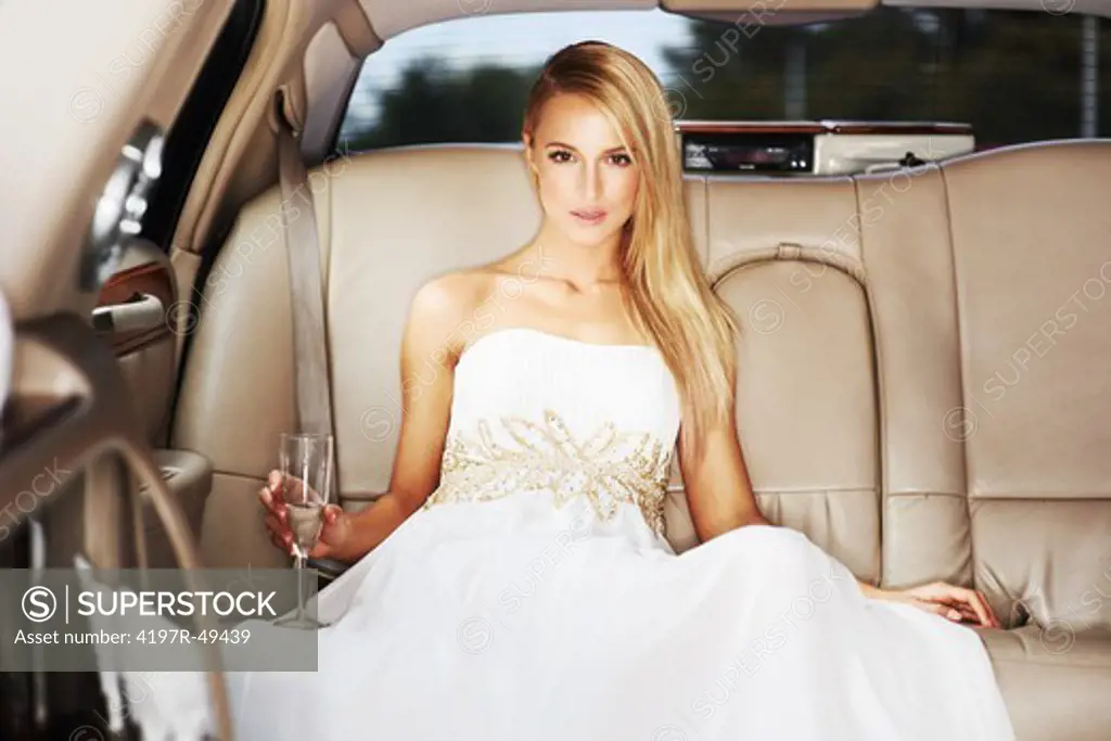 Portrait of a high society young beauty holding champagne in the back of a limousine