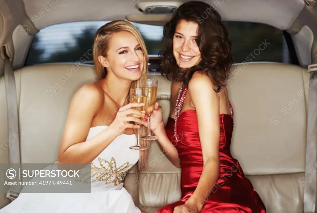 Two gorgeous young woman enjoying champagne in the back of a stretch limousine