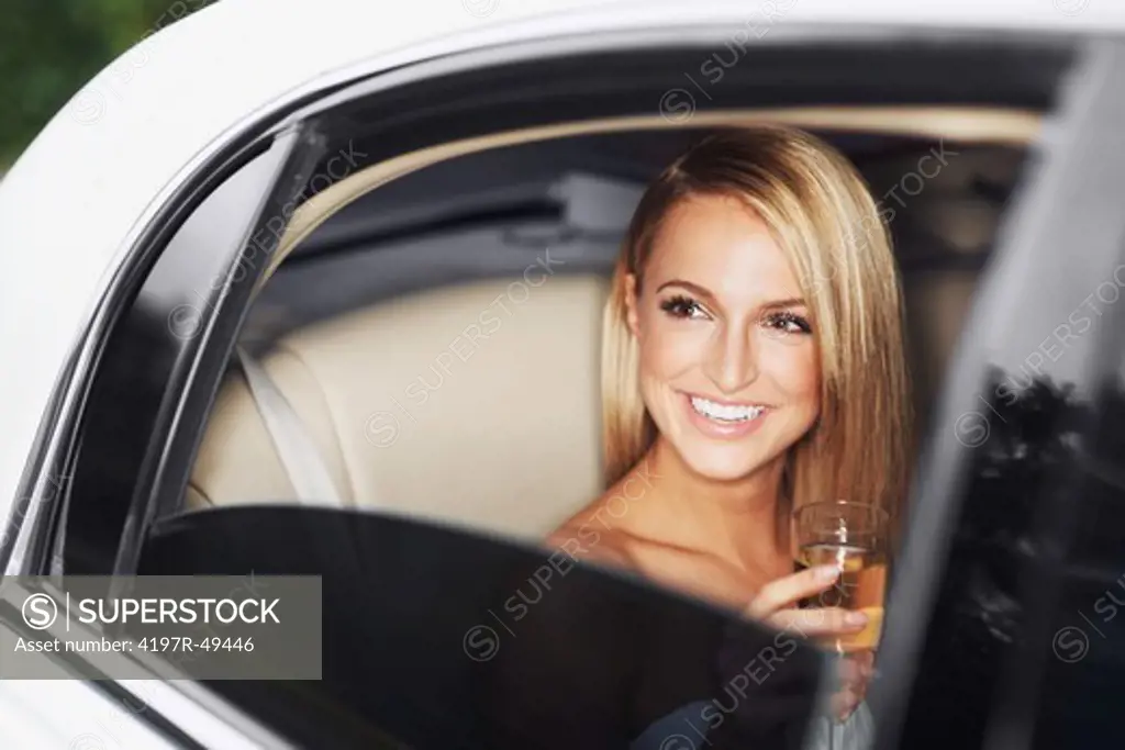 A gorgeous young woman seen through her limousine window drinking champagne