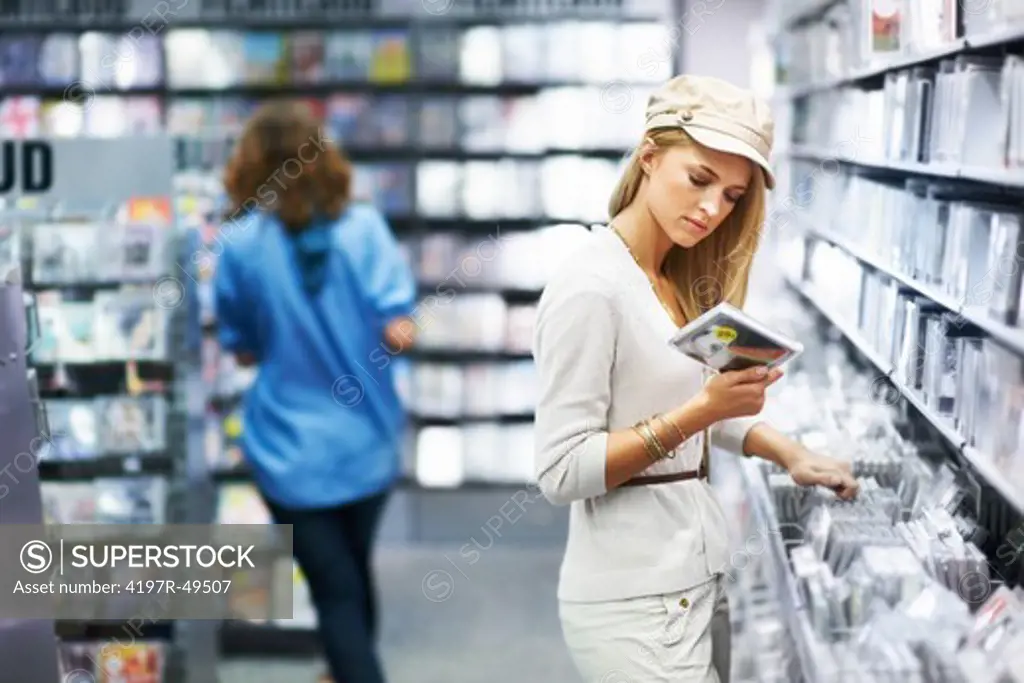 Beautiful young woman looking at a CD case while browsing a music store - Copyspace
