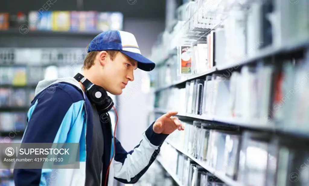 A trendy young guy wearing headphones and choosing music from the rack