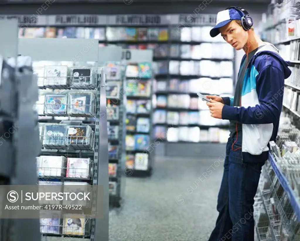 Portrait of a trendy young guy listening to music in a store - Copyspace