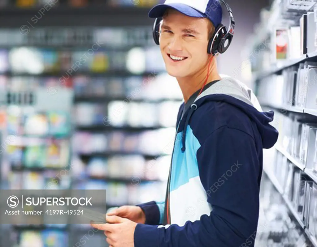 Portrait of a goodlooking, trendy guy enjoying music on his headphones at his favourite store