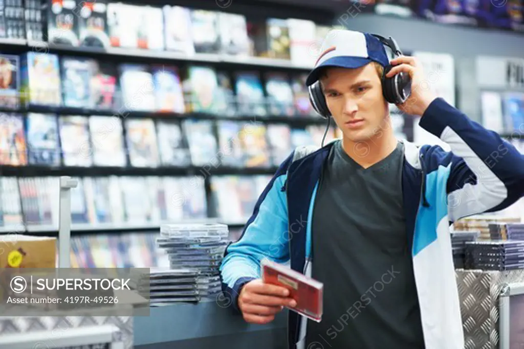A young trendy guy listening intently to some new music at his favourite music store - Copyspace