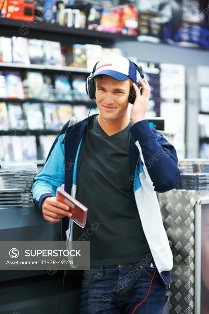 Portrait of a handsome trendy young guy listening to music on his headphones at the store