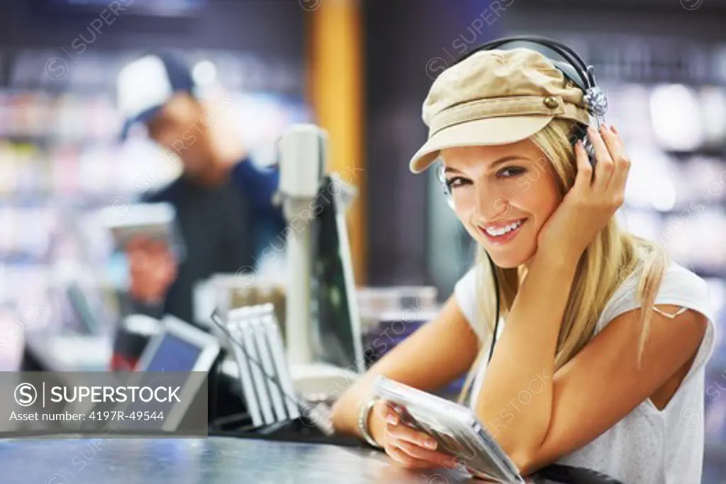 Portrait of a beautiful young woman wearing headphones and listening to her favourite music at her local store