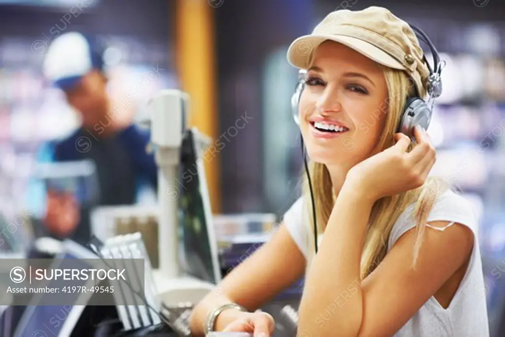 Portrait of a beautiful young woman wearing headphones and listening to her favourite music at her local store