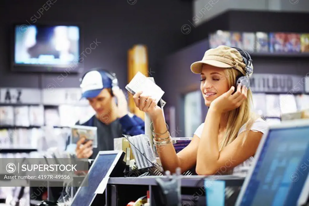 A young beauty wearing headphones getting into the music at her favourite local store