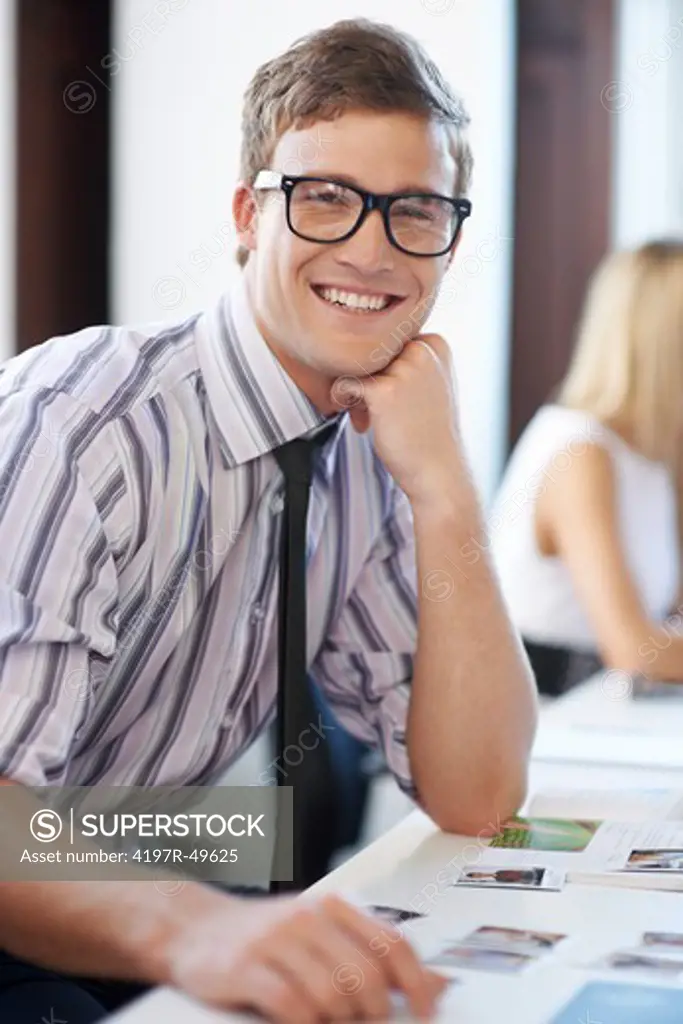 Portrait of an attractive hipster male employee sitting at his office desk