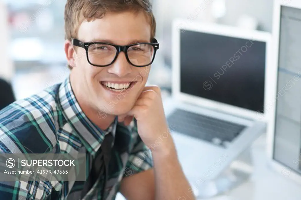 Portrait of smiling male geek employee with laptop in the background