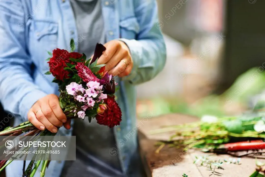 Cropped view of a florist's hands as she prepares a bouquet of flowers