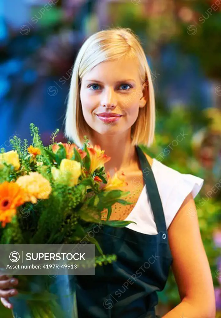 Portrait of a young flower shop assistant holding a flower arrangement in her hands