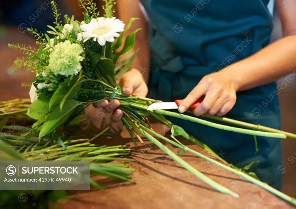 Cropped photo of a young woman cutting the stems of the flowers in her arrangement