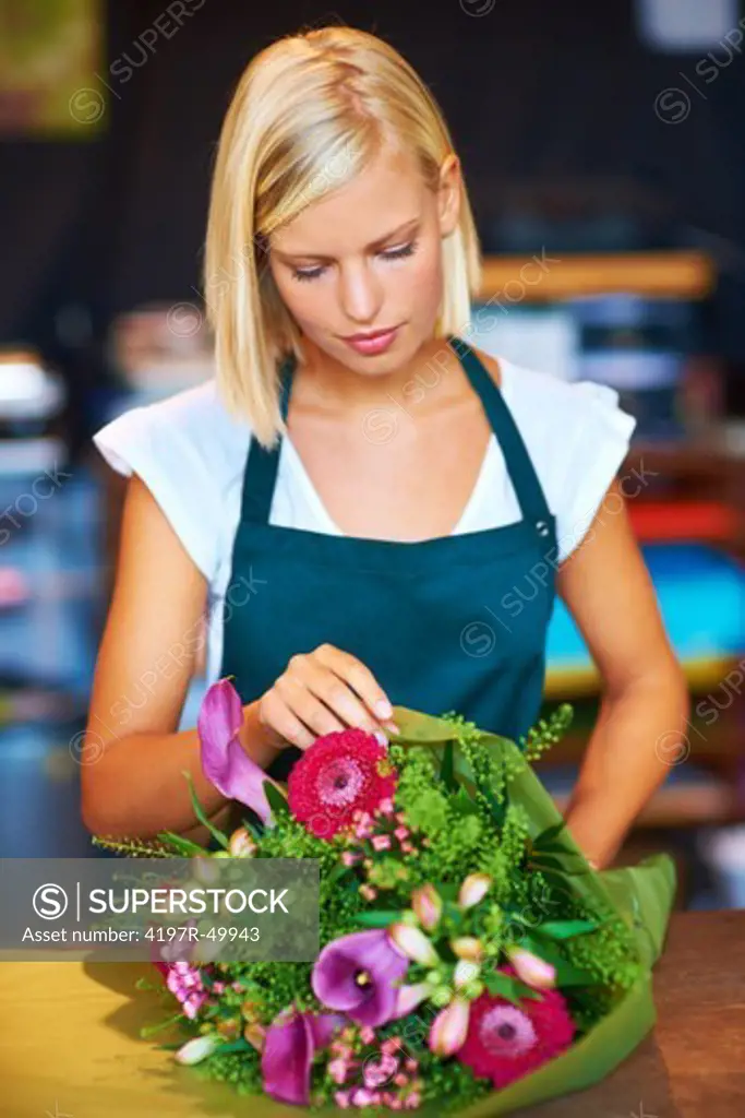 A young flower shop assistant putting the final touches on a bunch of flowers