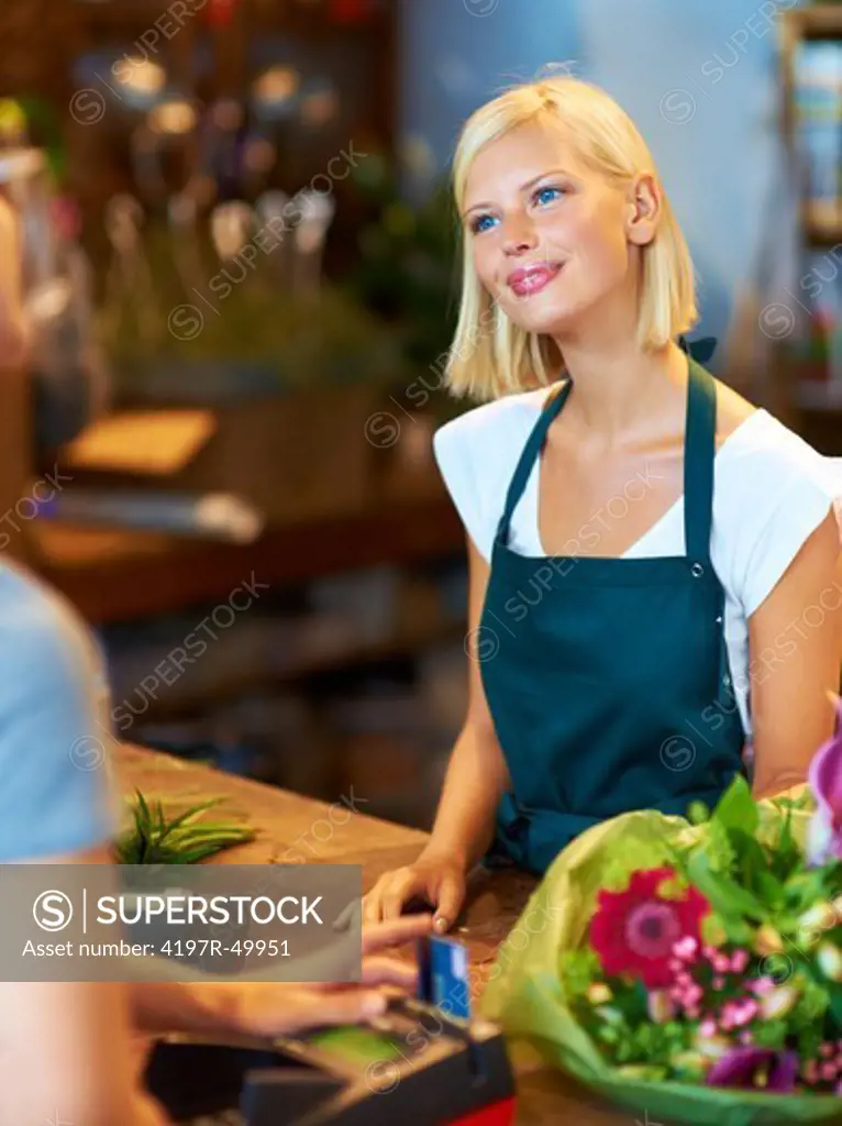 A young florsit talking to a customer as she buys a bunch of flowers