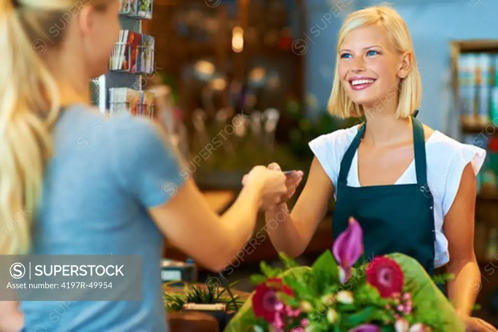 A young florist handing a customer her credit card back after payment