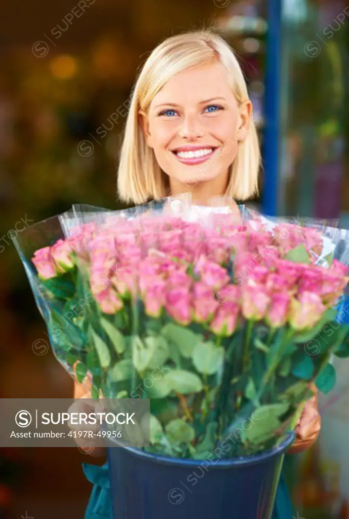 Portrait of a young florist holding a bucket filled with pink roses
