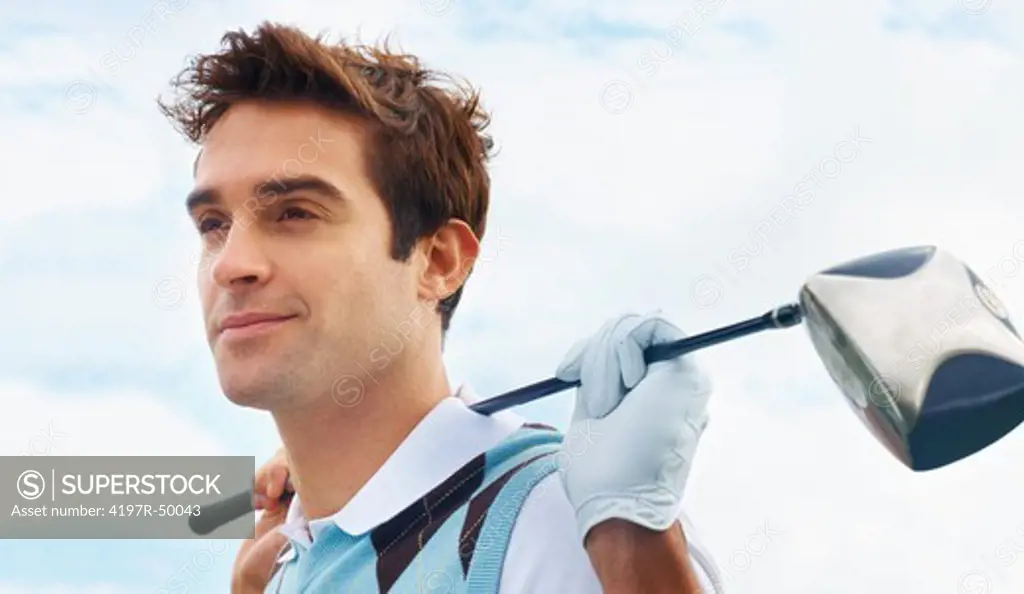 Young golfer looking away while holding his club