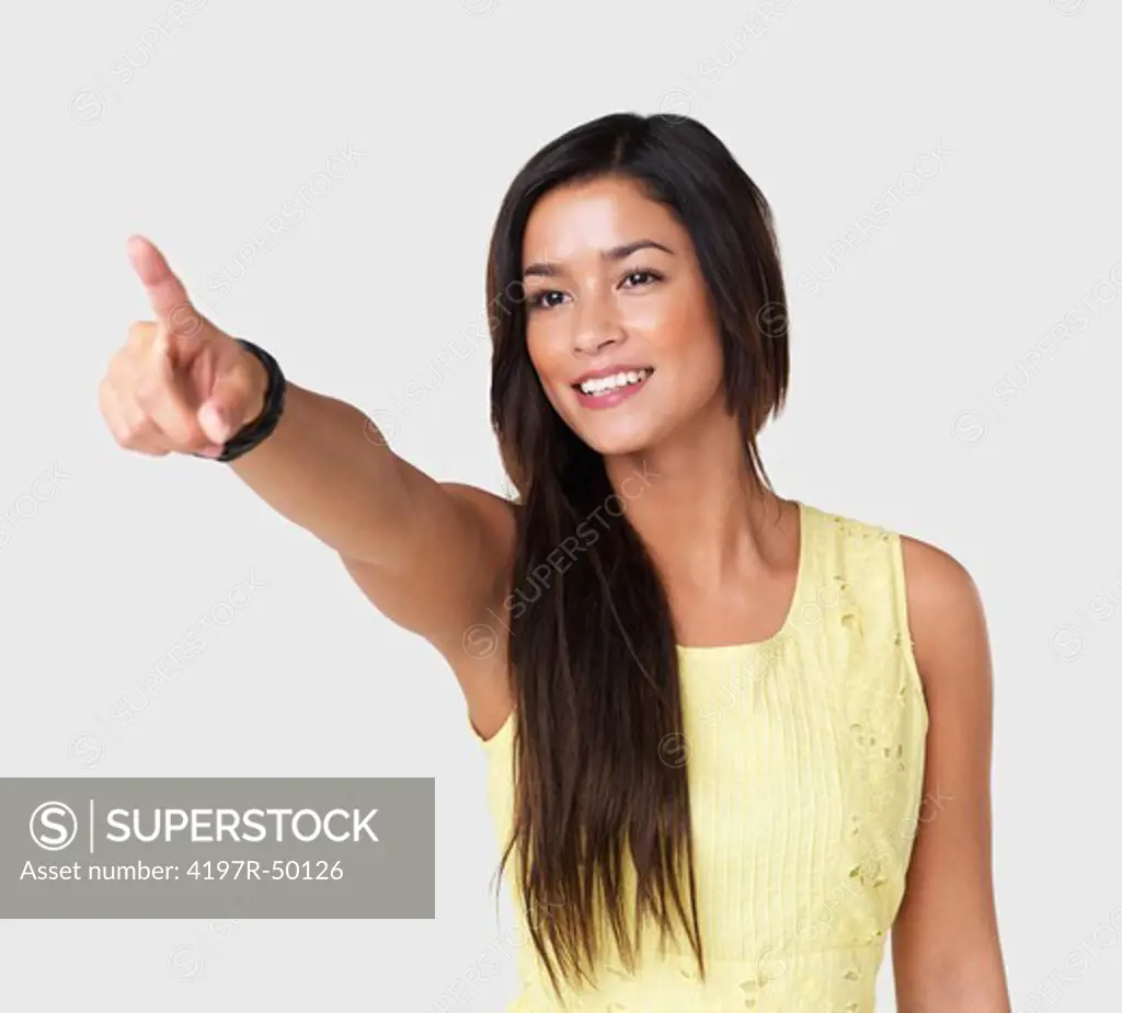 Cute young brunette points to copyspace while isolated on a white background