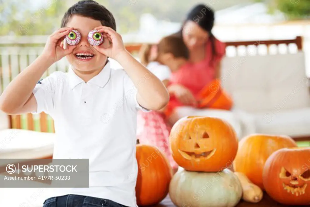 Young boy fooling around with Halloween props next to pumpkins