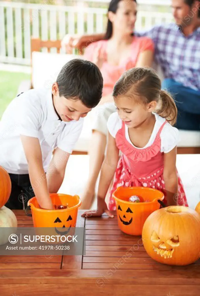 Brother and sister dig into their Halloween baskets for candy and treats