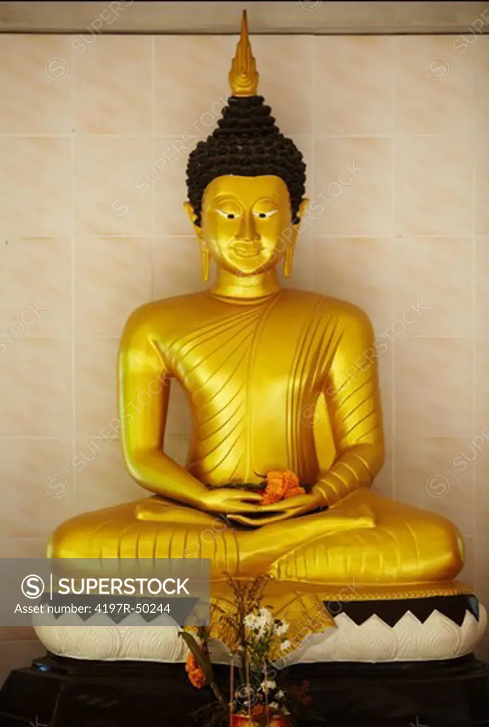 Golden Buddha in lotus position with palms upturned and offerings