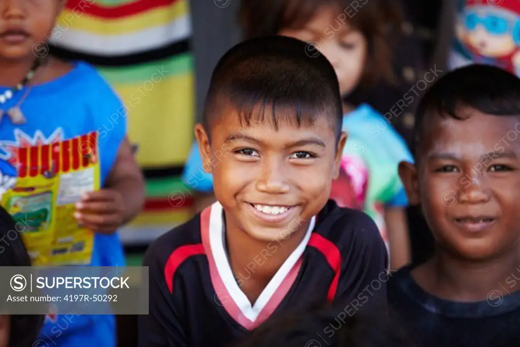 Portrait of young rural boy from Thailand smiling with other kids