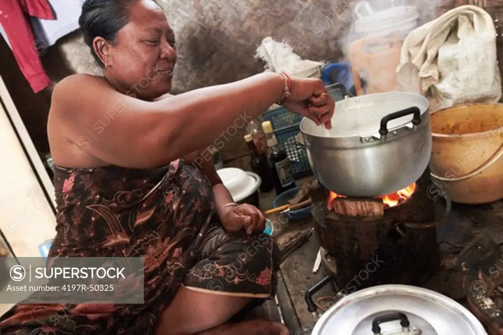A native woman stirring the food she is cooking over the fire
