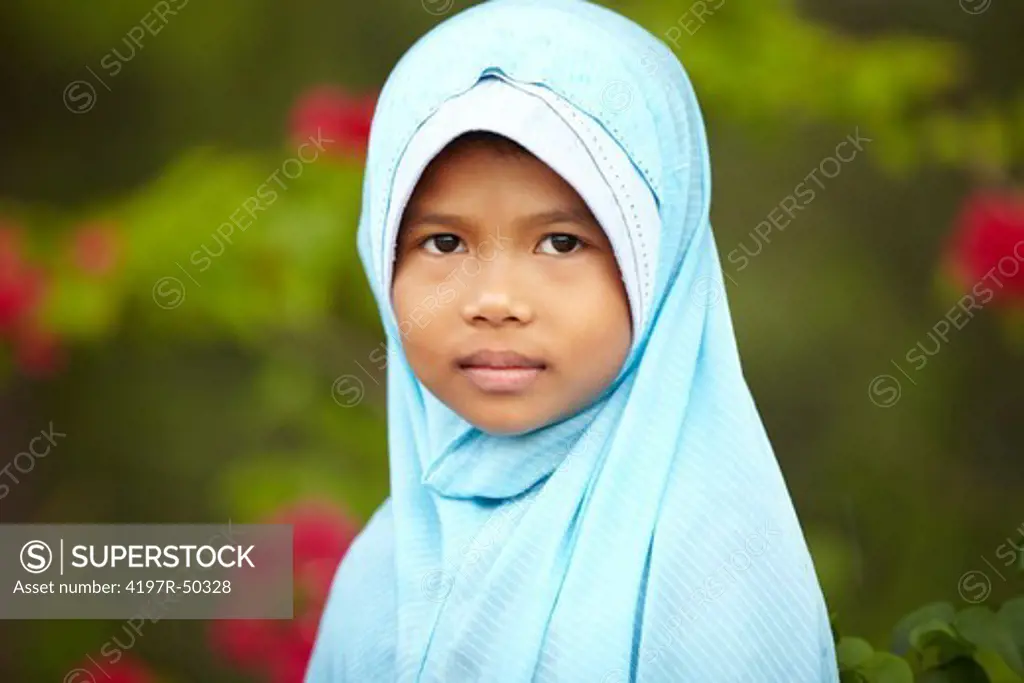A shy-looking girl wearing a blue headscarf