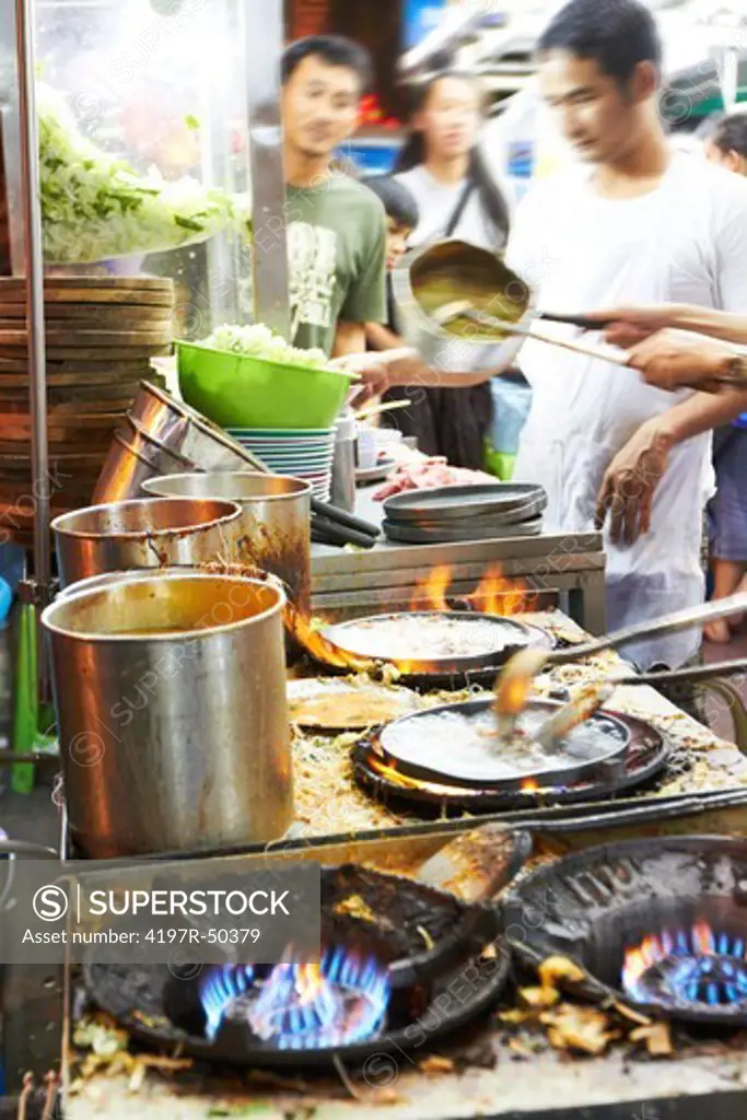 Busy chefs preparing food at a Thai streetmarket