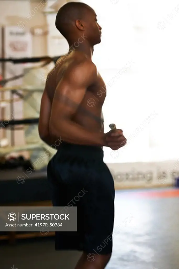 Fit African American boxer skipping to enhance his performance