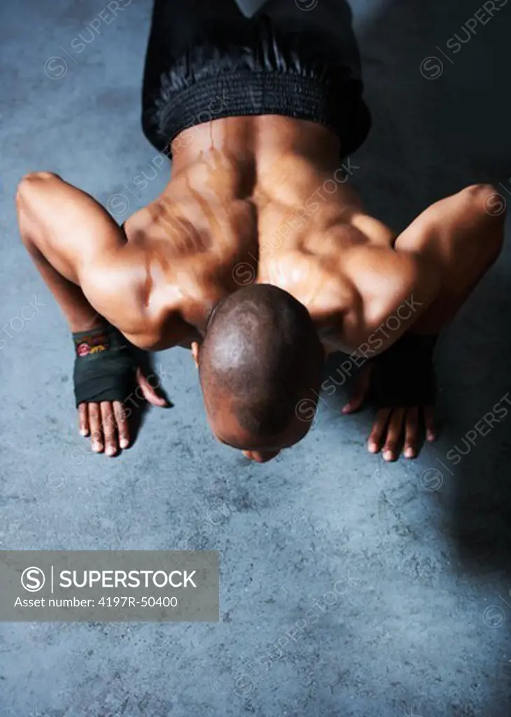 High-view of healthy young man doing push ups exercising againts a grunge floor
