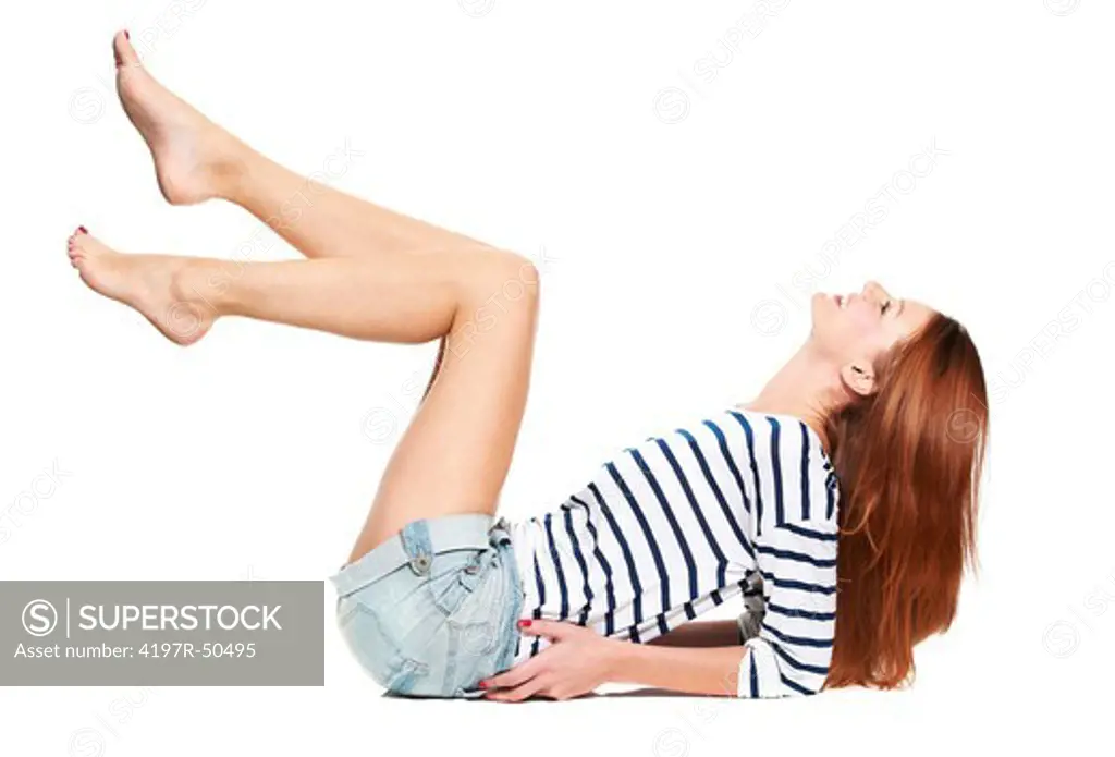 Side-view of a young woman leaning back on her elbows with her legs in the air