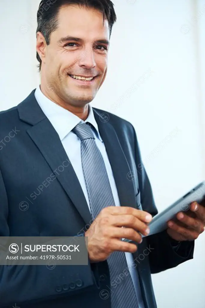 Handsome businessman smiling positively at you while using his digital tablet