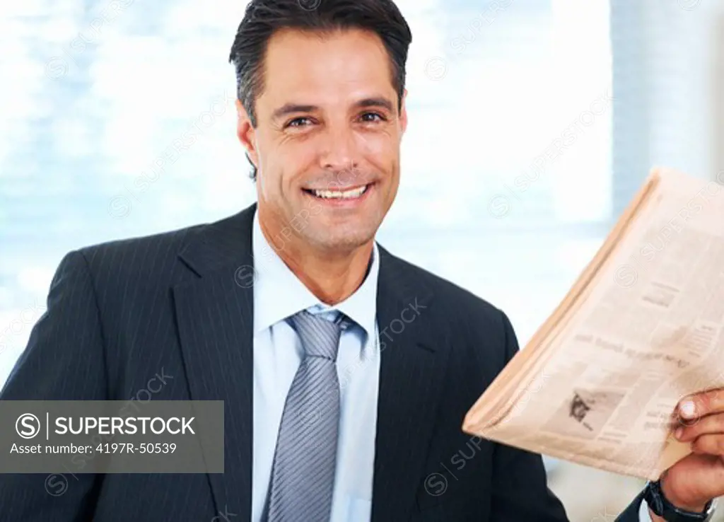 Handsome businessman smiling positively at you while holding his morning paper