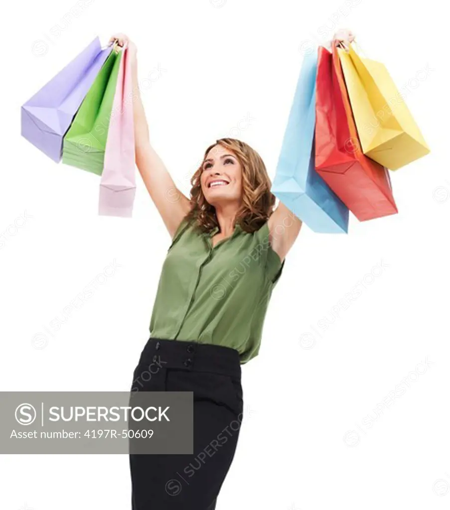 A cute young woman lifting her colourful shopping bags into the air triumphantly