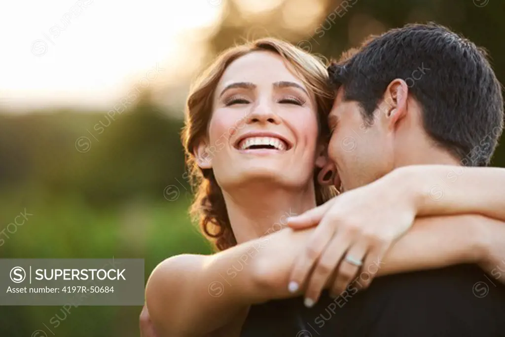 A beautiful bride smiling and laughing as she gives her husband a hug - Copyspace