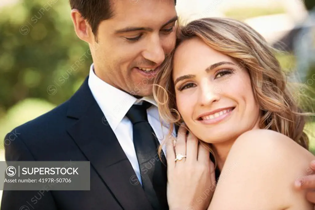 A beautiful bride leans on her husband's shoulder smiling contently