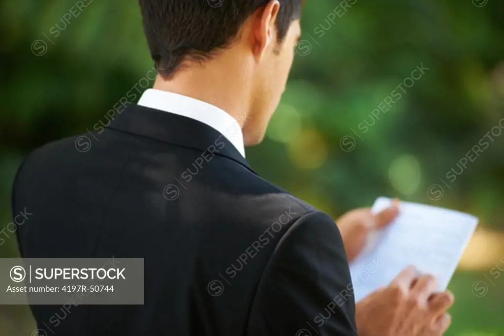 A groom stands reading over his vows before the wedding ceremony