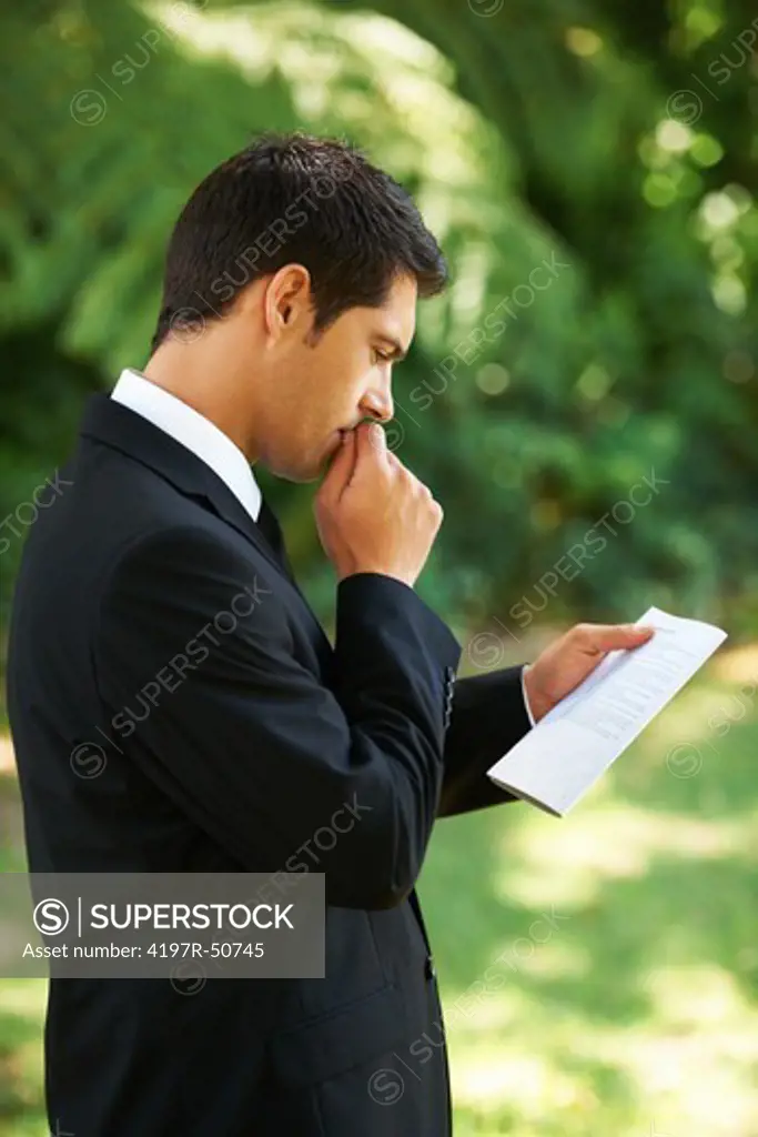 A nervous groom biting his nails while going over his vows before the wedding ceremony