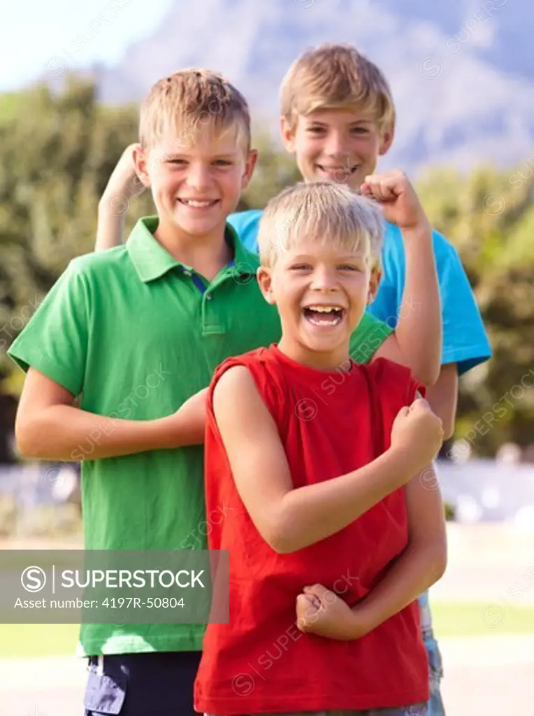Three young boys laughing and flexing their muscles for the camera