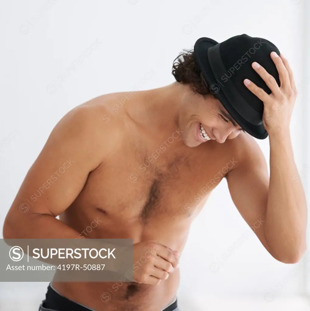 Gorgeous young man laughing without a shirt on and wearing a hat