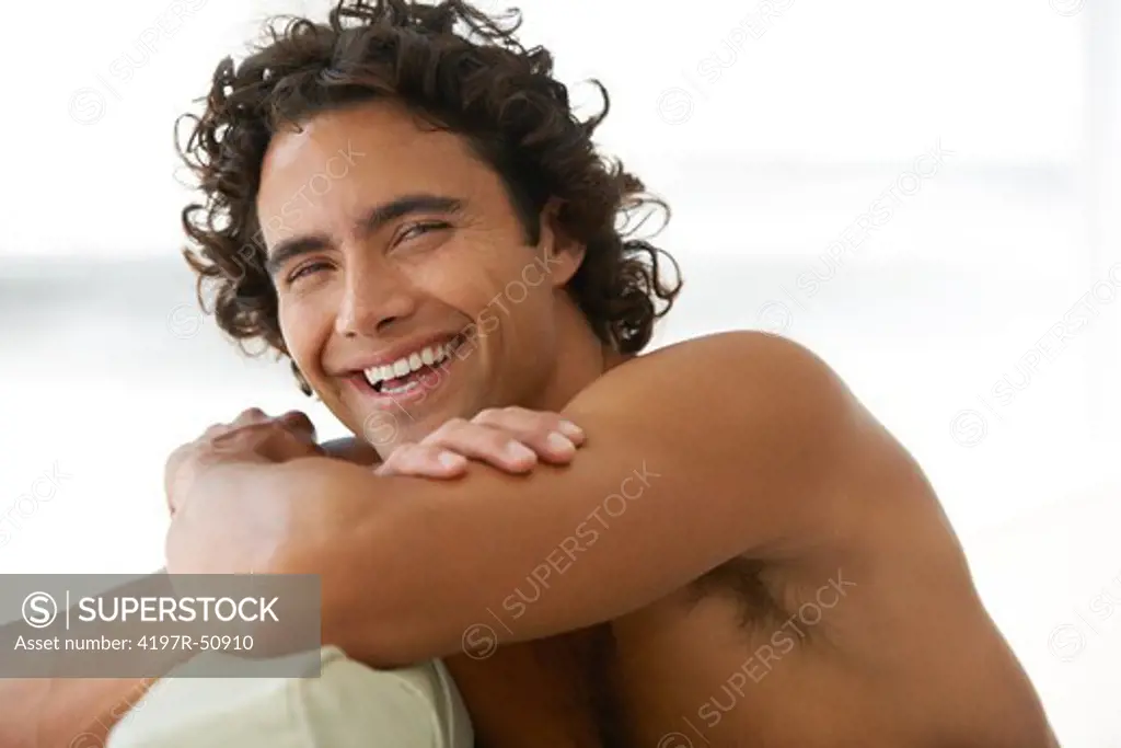 Gorgeous young man relaxing and smiling at you without a shirt