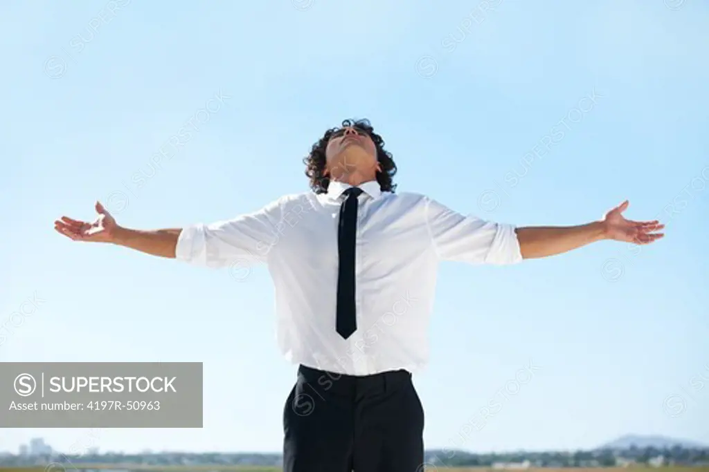 Businessman holding his arms out and turning his head towards the sky