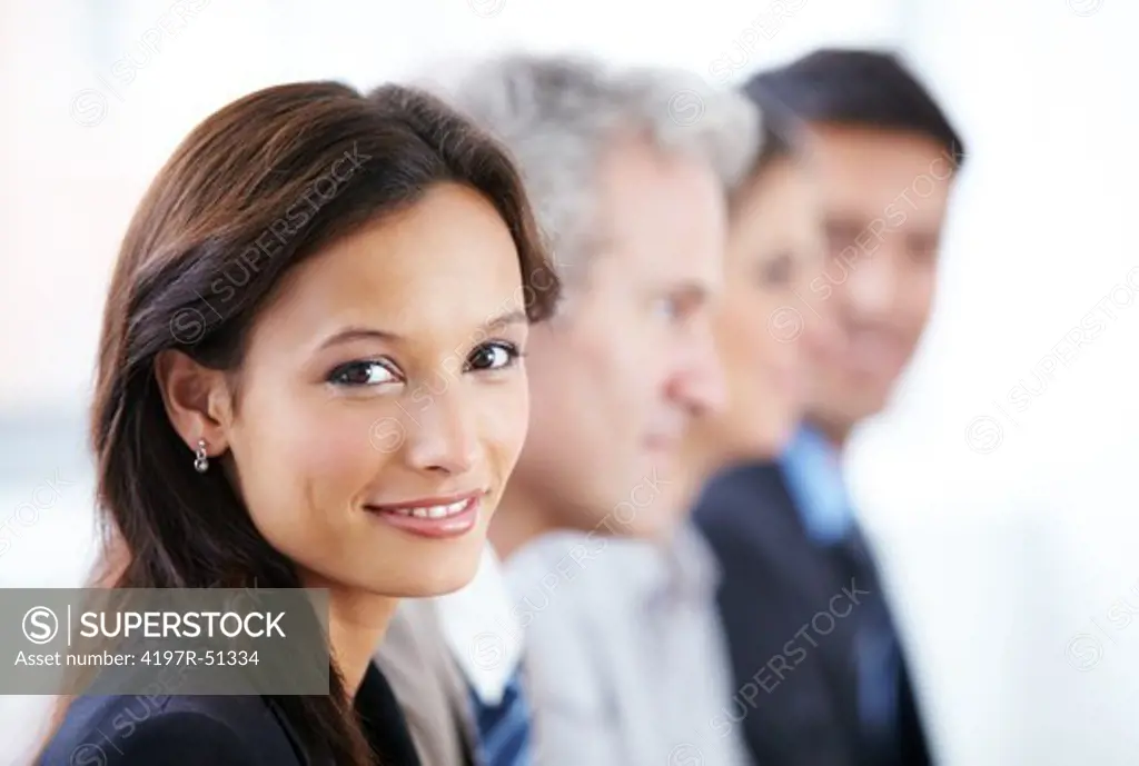 Lovely businesswoman smiling at the camera with her colleagues sitting in a row next to her