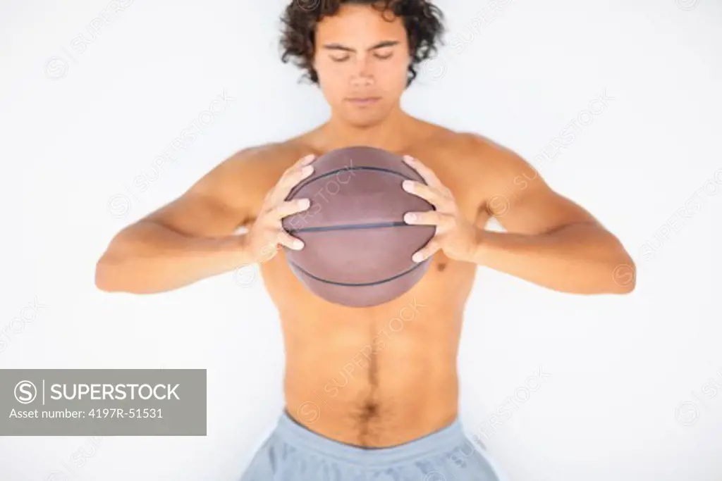Focused young sportsman holding a basketball while isolated on white