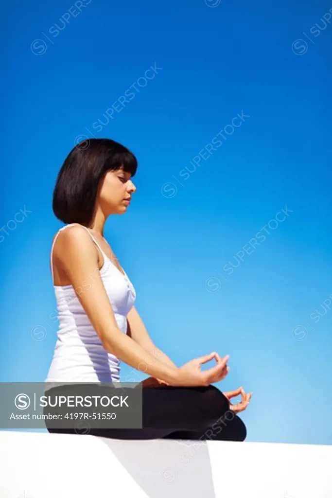 Side-view of a young woman sitting in the lotus position